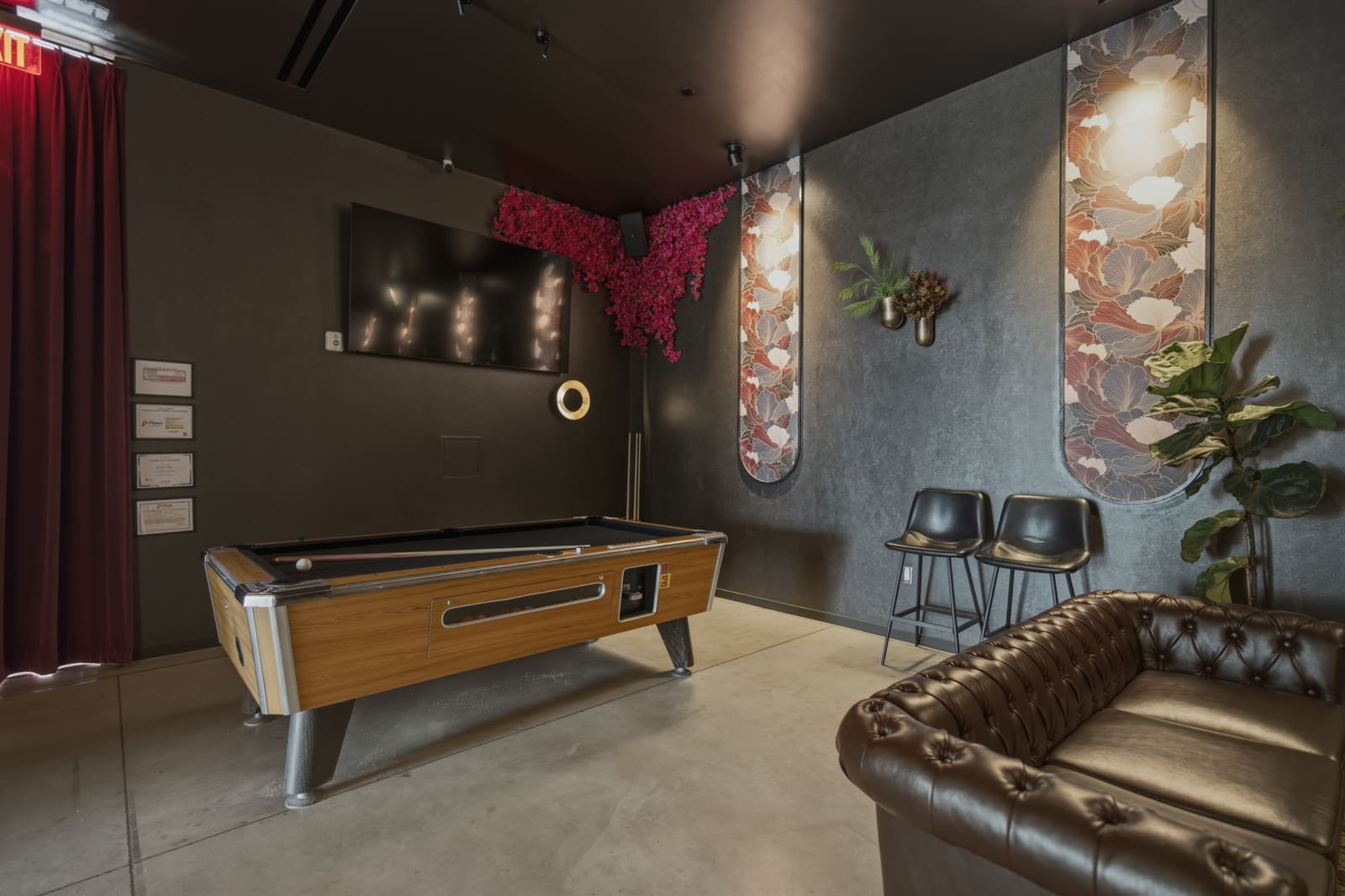 The lounge pool table with a screen mounted on the wall behind it and the stage-side curtain at the left