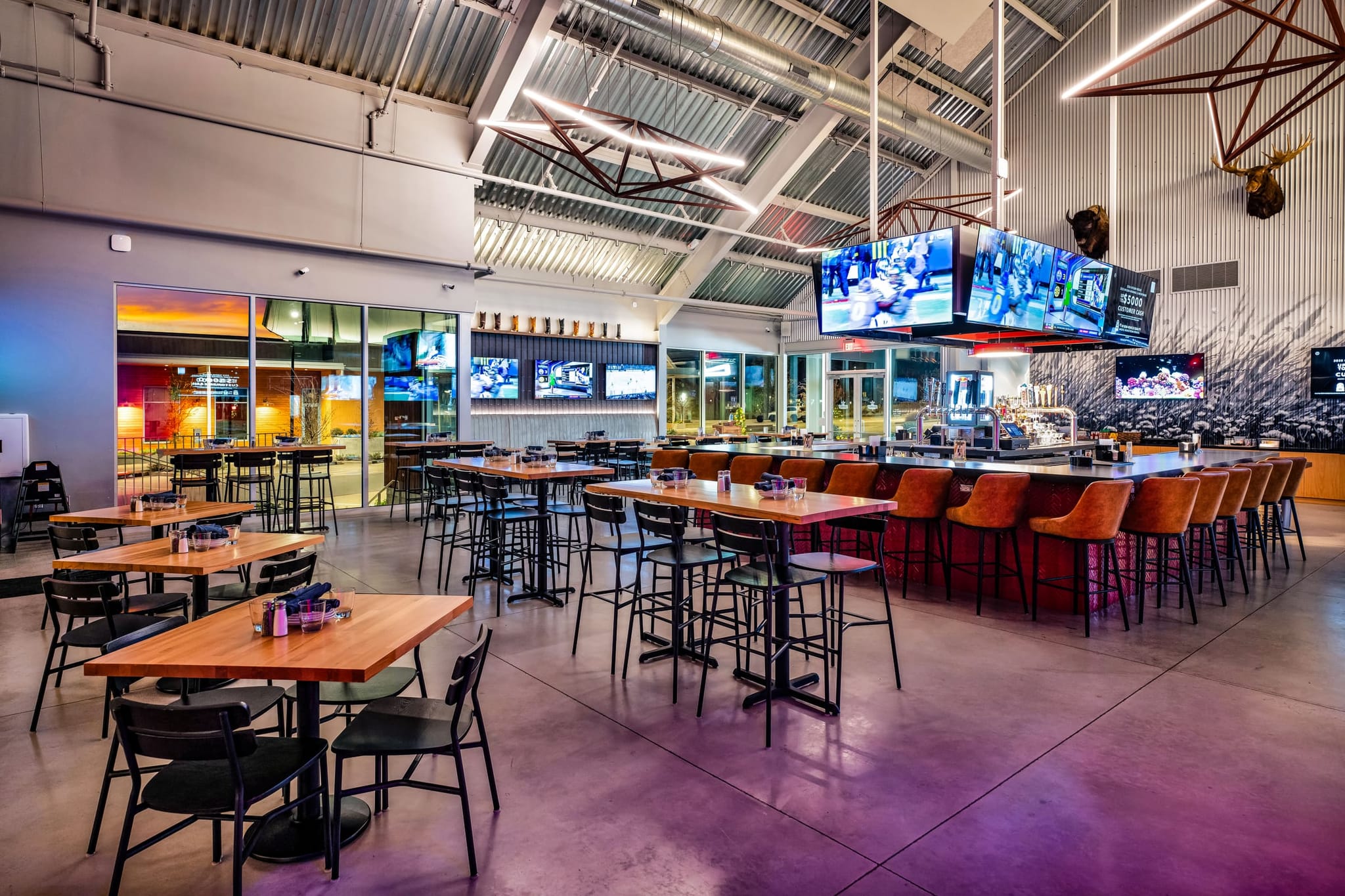 The main room at Assembly Icehouse, empty — the hall under its overhead rig, high-tops and the bar